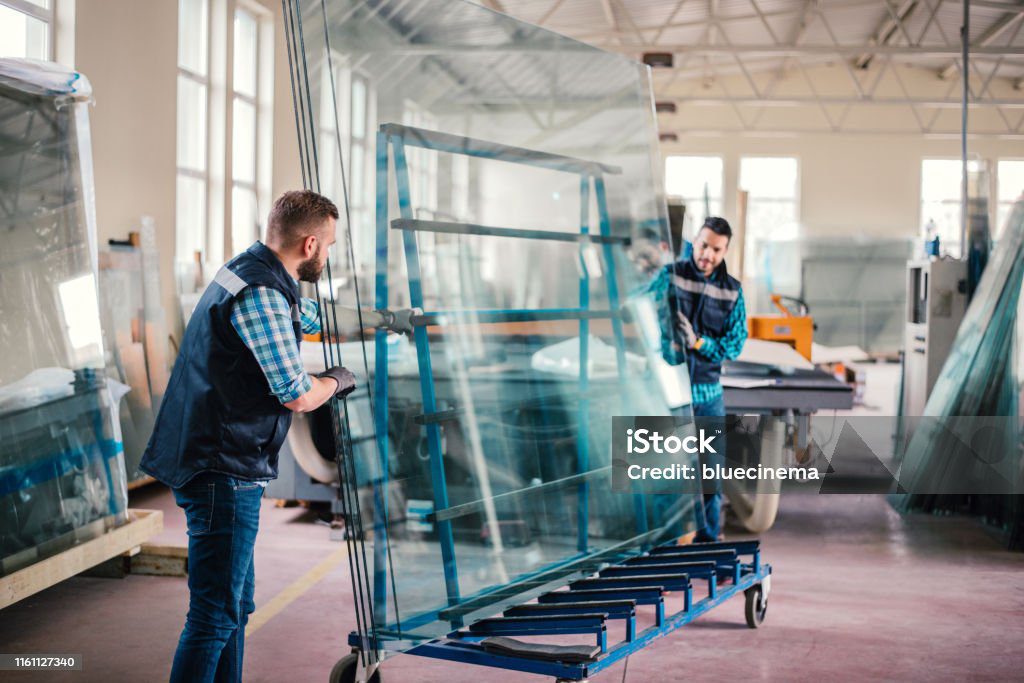 Workers packaging glass sheets in warehouse